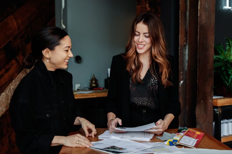 fashion line sheet: Two women smiling while working
