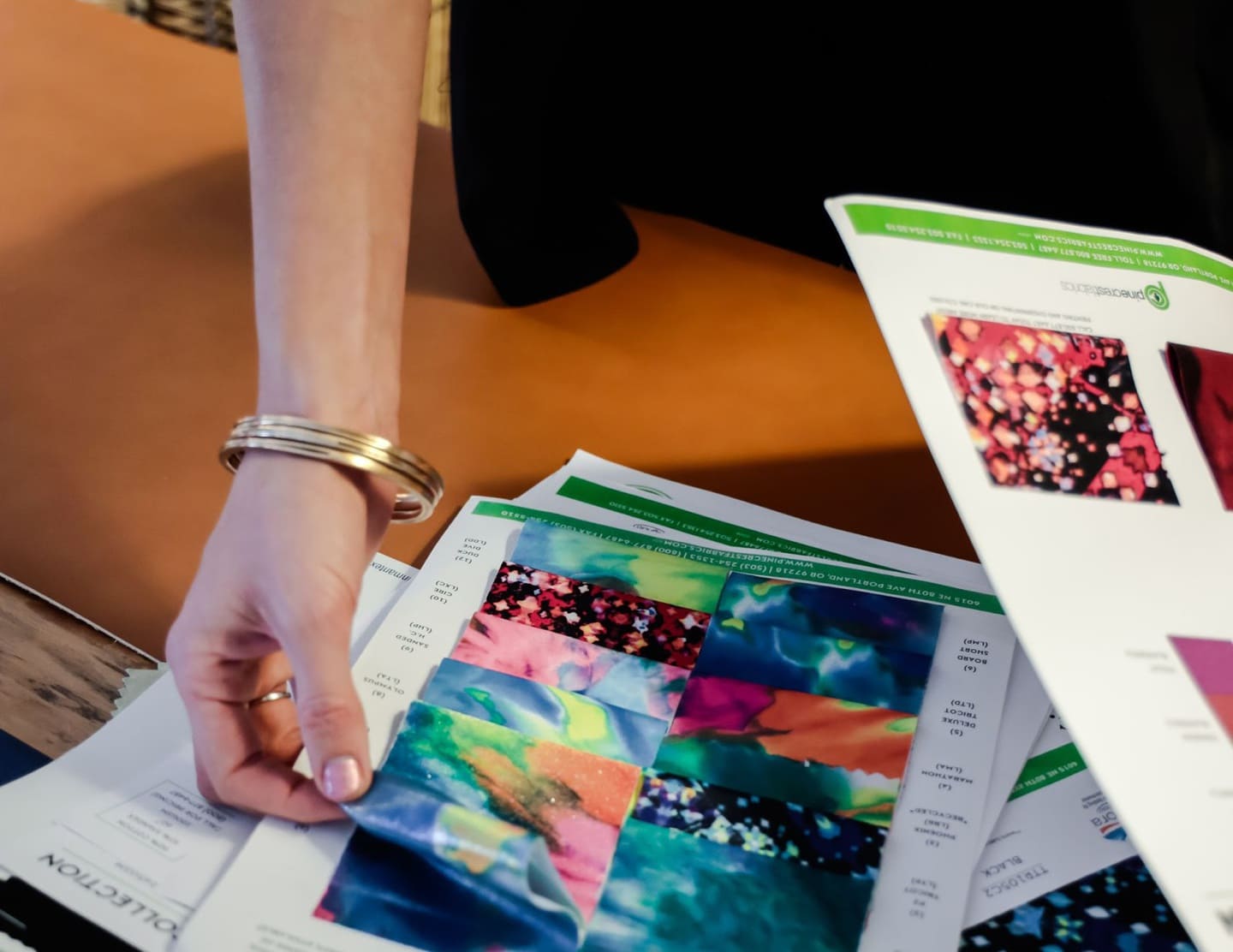 closeup of a fashion designer examining fabric swatches for a clothing line